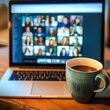 © Pornarun - laptop displaying video conference with multiple participants and coffee cup nearby creates cozy work environment