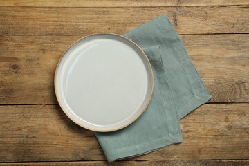 Wall Mural - Napkin and empty plate on wooden table, top view