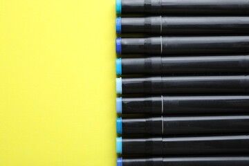 Wall Mural - Color double sided markers on yellow background, top view. Space for text