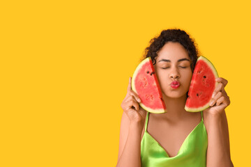 Wall Mural - Pretty young African-American woman with fresh watermelon on yellow background