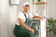 © Pixel-Shot - Male plumber fixing washing machine in bathroom