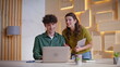 © stockbusters - Smiling colleagues video calling at business workplace. Cheerful woman and man