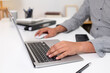 © jojo - Young man uses his hand to touch a laptop on his desk.