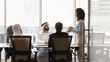© fizkes - Multinational businesspeople listening speech, presentation of young Brazilian female team leader, presenting review of company performance, gather together for strategy planning, new product launch