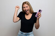 © Sergio - Excited blonde woman smiling, holding her phone