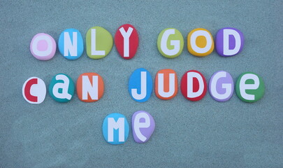 Wall Mural - Only God can judge me, creative message composed with multi colored hand painted stone letters over green sand