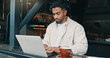 © WestLey/peopleimages.com - Thinking, laptop and man in restaurant, coffee and remote work with content creation. Person, writer and freelancer with pc, research for article and editing for cafe review and email notification