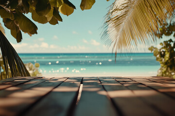 Wall Mural - Wooden tabletop overlooking tranquil tropical beach with palm leaves, glistening bokeh sea, and clear summer sky perfect for product display or vacation-themed design