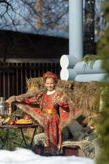 Wall Mural - A blonde girl in a national Russian costume on the Maslenitsa holiday. A beautiful russian girl in a national costume made of a fur cape and kokoshnik on the background of a hayloft. 