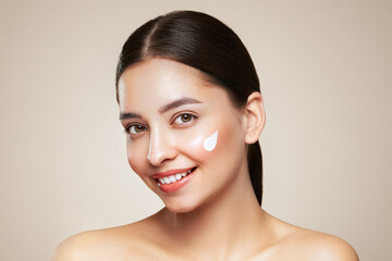 Wall Mural - beautiful young woman applying cosmetic cream treatment on her face isolated on background . girl wi