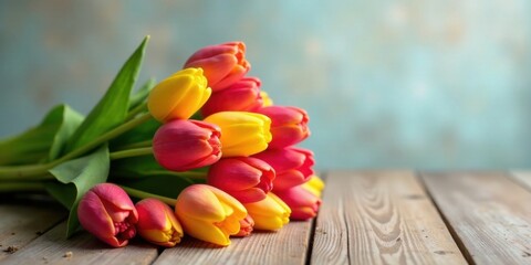 Poster - A vibrant bouquet of red and yellow tulips rests gently on a rustic wooden surface against a soft, blurred background.