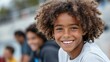 © SerPak - Smiling african young boy with curly hair in casual setting.