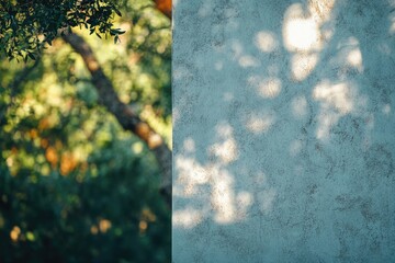 Poster - Blurred green foliage contrasts with a textured wall dappled with sunlight, creating a serene scene.