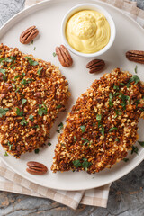 Wall Mural - Chicken cutlets are breaded in a delicious pecan crust and baked until perfectly crispy close-up in a plate on the table. Vertical top view from above