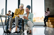 © NDABCREATIVITY - Disabled woman in wheelchair looking at computer, discussing startup project with interracial team