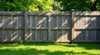 © parichart - Wooden fence bathed in sunlight against a backdrop of lush green foliage