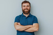 © ZaheerUDin - Portrait of a happy, smiling bearded man wearing a blue polo shirt, standing confidently with arms crossed against a white background, exuding a friendly and approachable demeanor