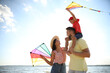 © New Africa - Happy parents and their child playing with kites near sea. Spending time in nature