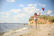 © New Africa - Cute little child with kite running on beach near sea. Spending time in nature