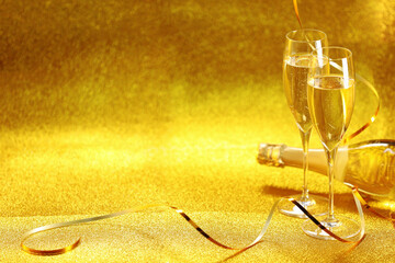 Wall Mural - Champagne in glasses and bottle on golden background. Space for text