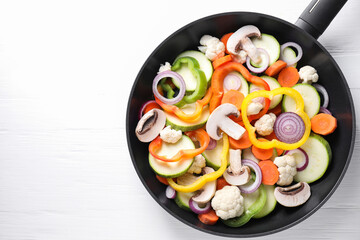 Wall Mural - Frying pan with mix of vegetables and mushrooms on white wooden table, top view. Space for text