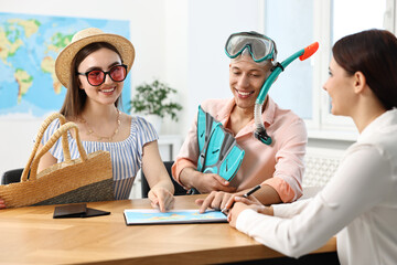 Sticker - Happy couple planning vacation with travel agent at wooden table in office