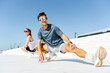 © muse studio - Two people stretching on a sunny day in an outdoor urban setting while wearing sporty attire and sunglasses
