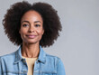 © Chari - Woman with natural curly hair wearing denim jacket and smiling against a neutral background