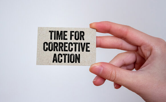 Time for corrective action message written on a card in hand. Conceptual time for corrective action symbol. Copy space.