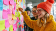 © Number One Studio - Creative brainstorming session with colorful sticky notes on wall. Three young women collaborate, sharing ideas and smiling, showcasing teamwork and innovation