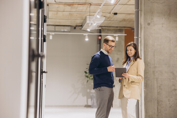 Wall Mural - Businessmen consulting digital tablet in office hallway, analyzing work strategy and sharing professional insights