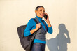 © Paula - Smiling woman with short hair in casual attire on phone call with a backpack
