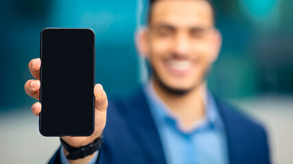 Modern technologies and business concept. Unrecognizable businessman showing smartphone with empty screen, recommending brand new mobile application for business, finance, selective focus