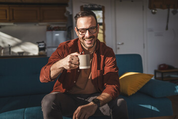 One adult caucasian man sit at home and hold cup of coffee enjoy home