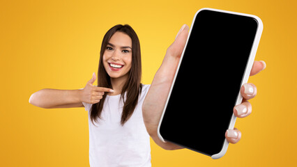 Aufkleber - Try This App. Portrait of smiling lady holding smartphone with black blank screen in hand, showing device close up to camera and pointing finger at gadget with empty free space for mock up, banner