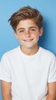 © Imagine Crane - A young boy with a white shirt and brown hair is smiling for the camera. The boy's smile is bright and cheerful, and he is happy and content. The blue background adds a sense of calmness
