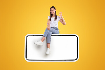 Aufkleber - Cheerful Woman Sitting On Big Smartphone With Blank White Screen And Gesturing Okay Sign, Happy Young Lady Recommending New App Or Website, Isolated On Orange Background, Mock Up, Creative Collage