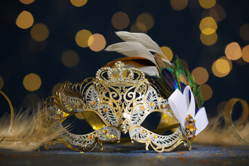 Wall Mural - Beautiful carnival mask on table against dark background with blurred lights, closeup