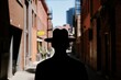 © Outkast - Silhouette of a Man in a Hat Walking Through an Urban Alleyway with Buildings in the Background