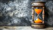 © amorn_m - Vintage Hourglass with Orange Sand on a Textured Background Symbolizing the Passage of Time