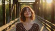 © Christian Bunge - young pretty woman stands on a bridge with her eyes closed and a smile on her face, enjoying the sun's rays, concept: take care of yourself, 16:9