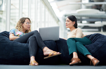 Poster - Creative, conversation and women on bean bag with laptop, collaboration or schedule planning. Relax, advice and business people in modern office for online project ideas, teamwork or design at agency