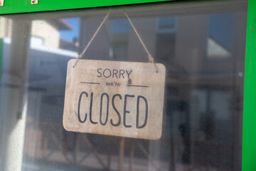 sorry we are closed text sign hanging inside a restaurant store office or other