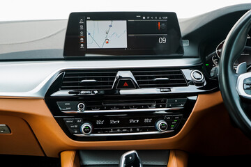 Inside a Brand new hatchback car from the factory with the central display monitor showing the GPS Sat Nav with passenger airbag lights on and media buttons and knobs. Hazard light button with Screen