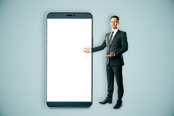 Wall Mural - Businessman presenting a giant smartphone with a blank white screen.