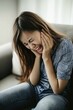 © Road Red Runner - Joyful Asian girl laughing while posing at home on a cozy couch during a video call with friends