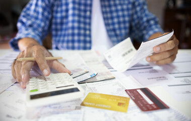 Asian man sitting at desk calculate receipt of expenses and all loan bills and try to find money to pay credit card debt, financial problem and inflation economy concept