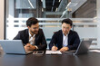 © Liubomir - Two business people inside the office, signing a contract. Men in business suits inside the office, doing paperwork, sitting in a business meeting room.