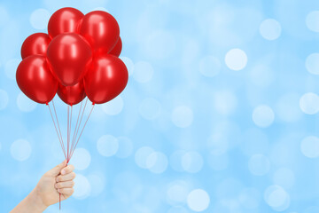 Aufkleber - Female hand holding bunch of shiny red balloons on blurred blue background. Empty space for text