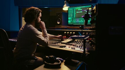Fototapete - Music producer fixing coiled cable inside amplifier or audio compressor, prepares control room technical equipment for a recording session. Sound engineer works on producing tracks. Camera B.